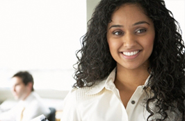 A female co-op student in a workplace smiling